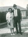 Lambert and May McBride standing on a footpath, their house can be seen in the background of the photo. 